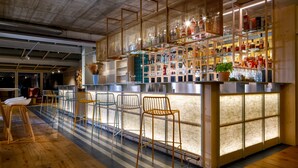 A bar area with wooden chairs, a bar counter, and shelves stocked with bottles.