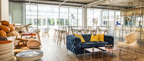 Een ruim, modern interieur met een grote zithoek, houten vloeren en een keuken die zichtbaar is door grote ramen.