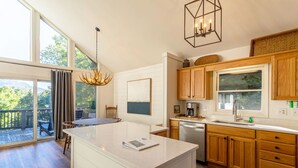 Una cocina moderna con armarios de madera, una isla grande y un comedor con vistas al exterior.