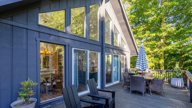 Una casa moderna con terraza, ventanas amplias y mobiliario exterior.