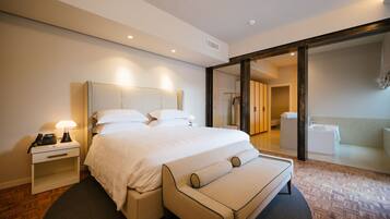 A modern hotel room with a large bed, bedside tables, a mirror, and a view of the bathroom.