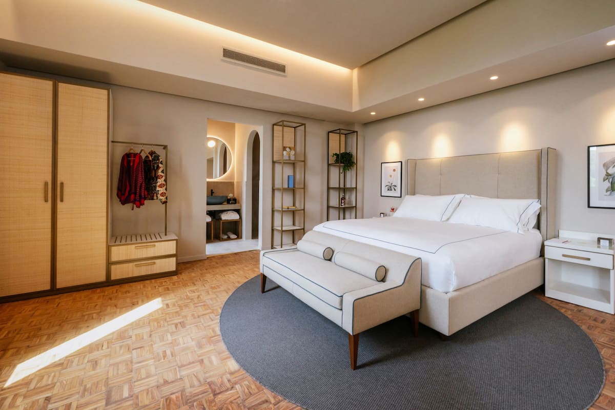 Un dormitorio moderno con una cama grande, un armario, una tocador y una estantería.