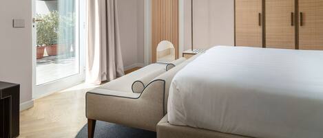 A modern hotel room with a large bed, a wardrobe, and a seating area by the window.