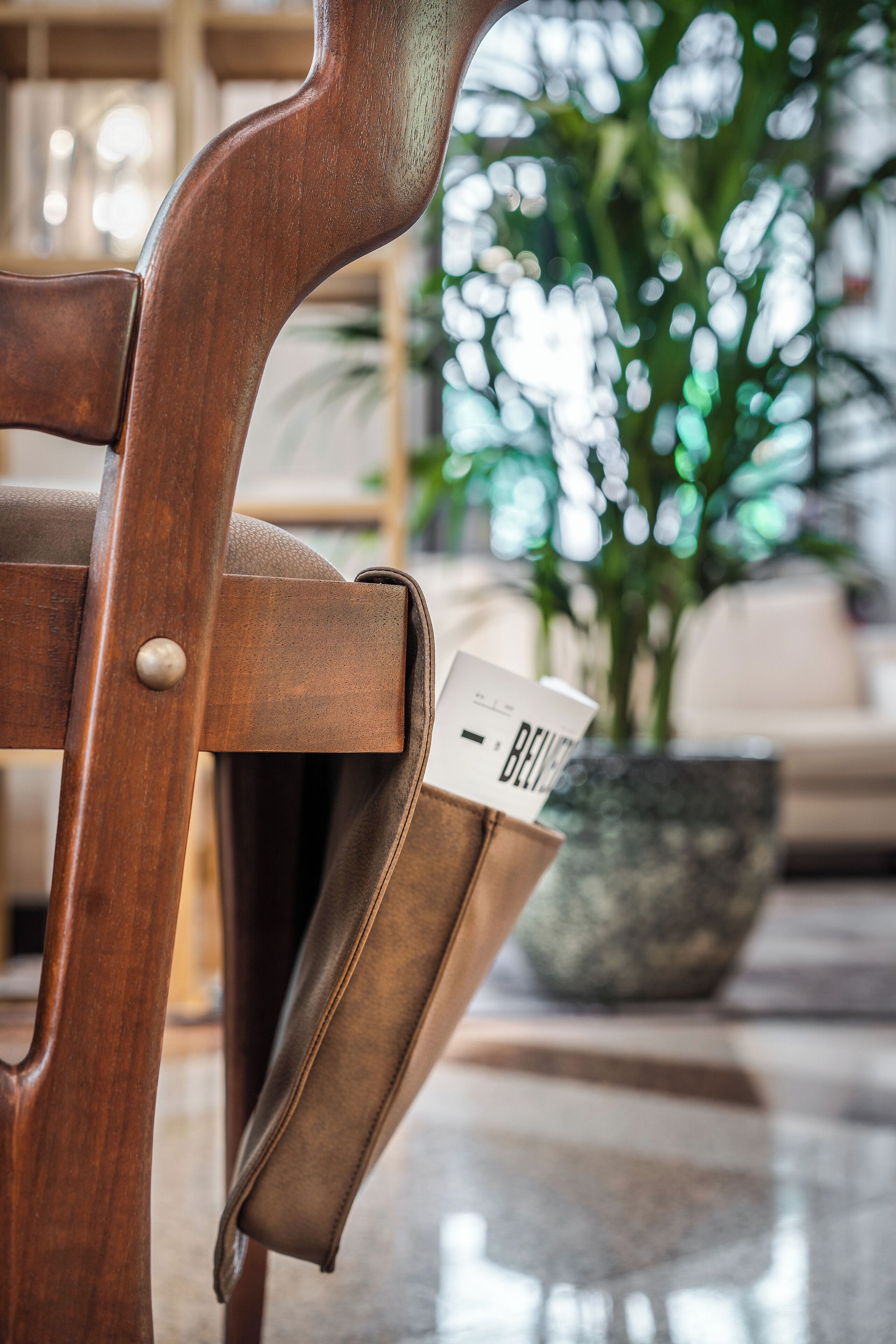 A wooden chair with a leather seat and a name tag.