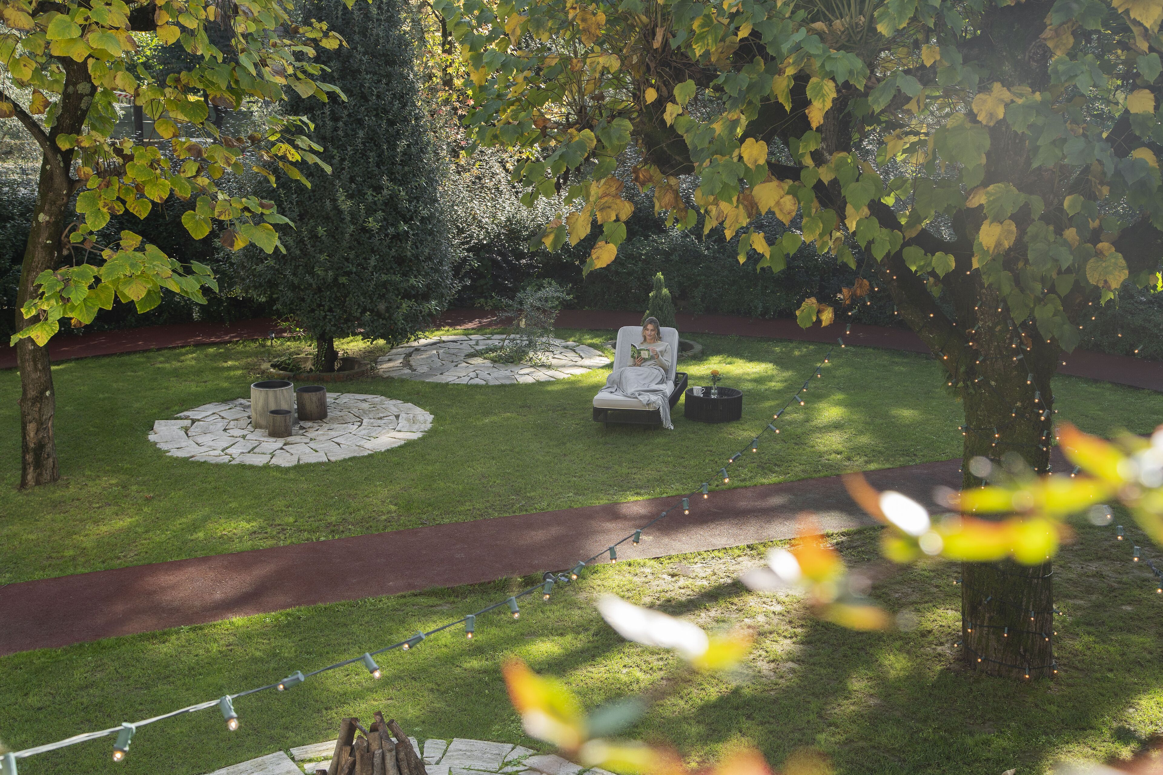 A well-maintained garden with a paved path, seating area, and a circular stone feature.