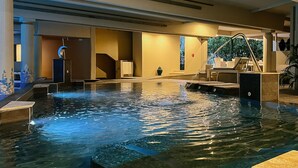 Ein Wellnessbereich mit Pool, Wasserspiel, Sitzgelegenheiten und Blick ins Freie.