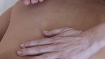 Une personne reçoit un massage du dos, effectué à la main, et une coupelle d’huile est utilisée.