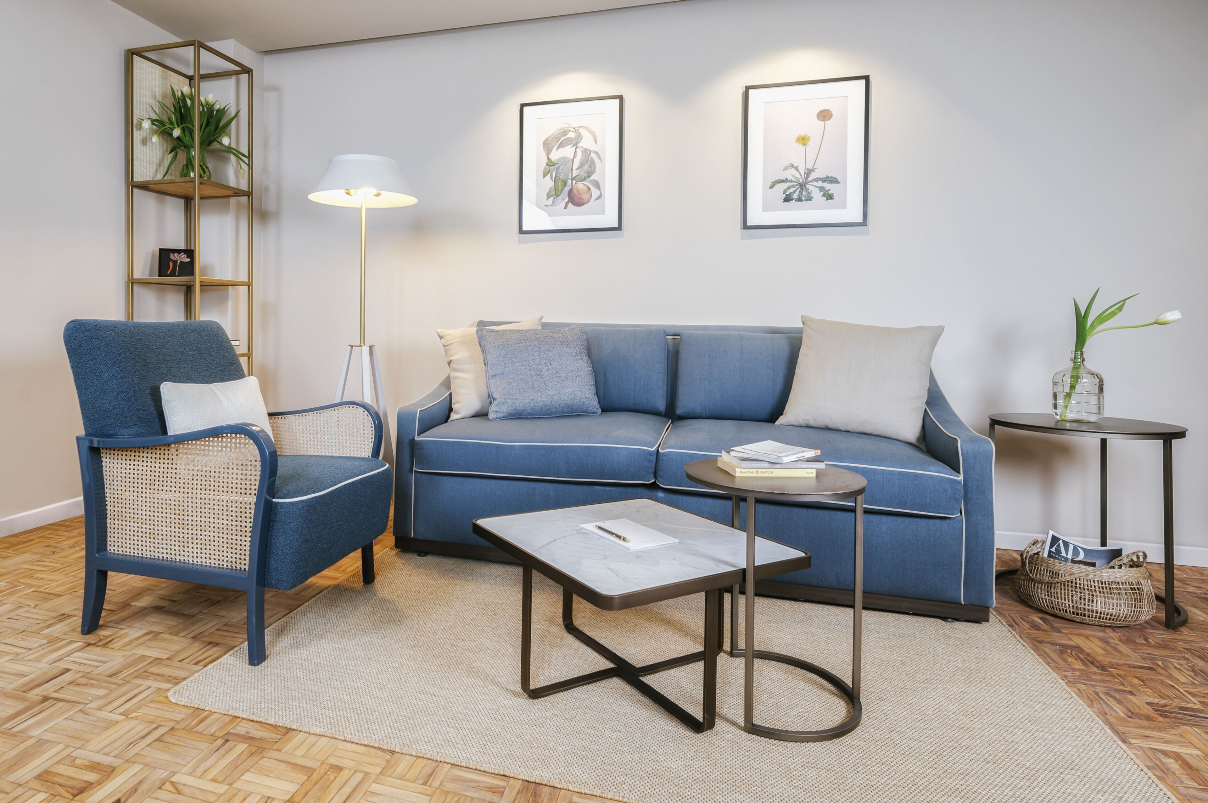 A living room with a blue sofa, a blue armchair, a small round table, and a floor lamp.