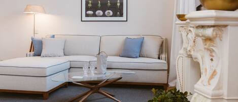 A modern living room with a sectional sofa, a glass coffee table, a floor lamp, and a framed floral artwork on the wall.