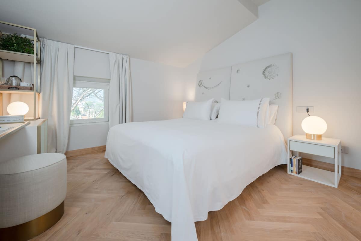 Un dormitorio moderno con una cama grande, mesitas de noche, un escritorio y una ventana con cortinas.