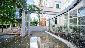 Un espace extérieur abrité, doté d’un sol en béton, de plantes en pot et d’une pergola en bois.