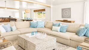 A modern living room with a sectional sofa, a coffee table, and a dining area in the background.