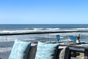Un balcon avec vue sur l’océan, agrémenté d’une table décorée d’objets et de coussins.