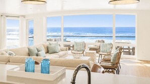 A spacious living area with a large window overlooking the ocean, furnished with a sofa, chairs, and a coffee table.