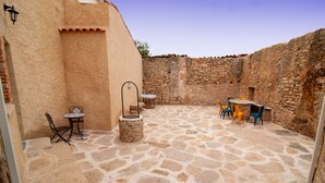 A courtyard with stone flooring, a table with chairs, and a small table with a chair. - Vintage Cottage With Large Yard (Cerezal de Peñahorcada)