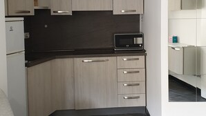 A modern kitchen with light wood cabinets, a black countertop, and a microwave. - Lupetta apartment (Milan)