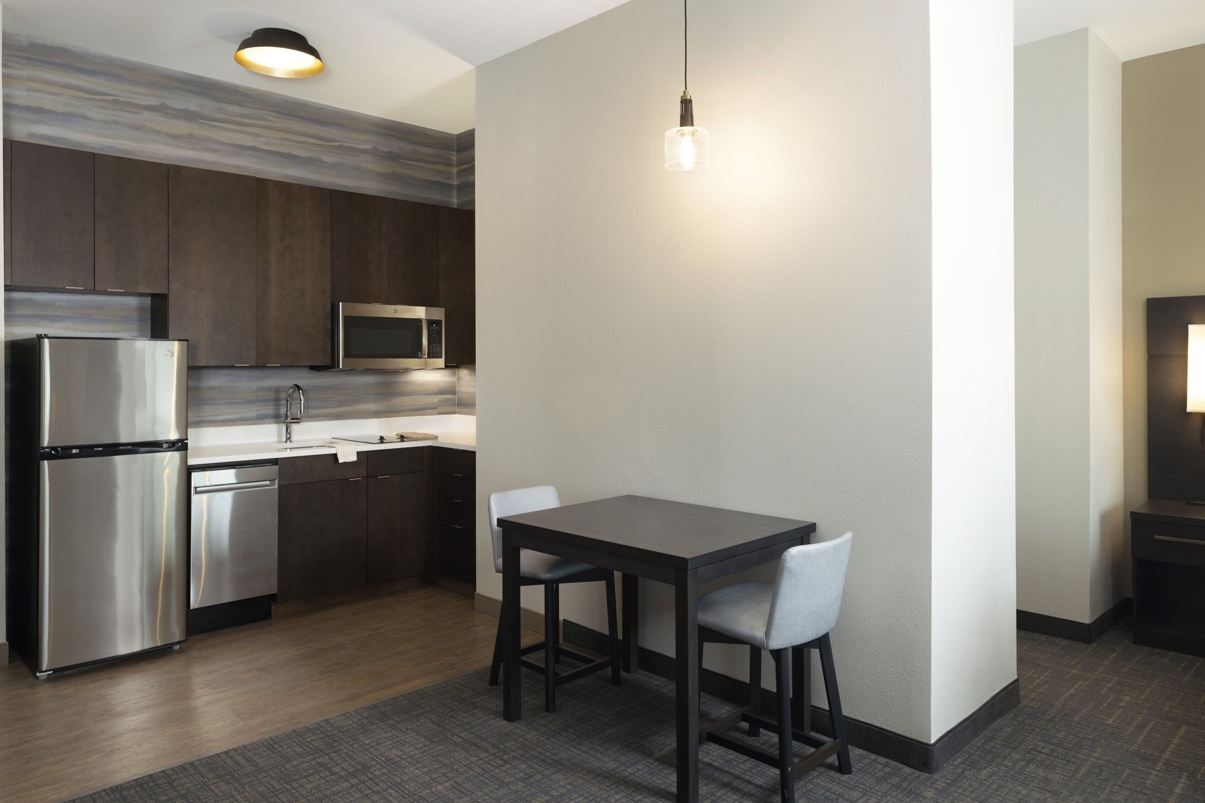 A modern kitchen with stainless steel appliances, a dark wooden countertop, and a dining area with a table and chairs.