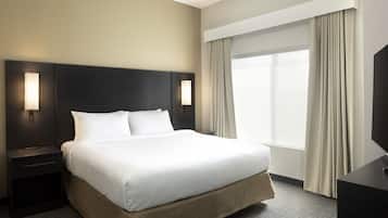 Hotelkamer met een groot bed, twee nachtkastjes met lampen, een flatscreen televisie en een groot raam met gordijnen.