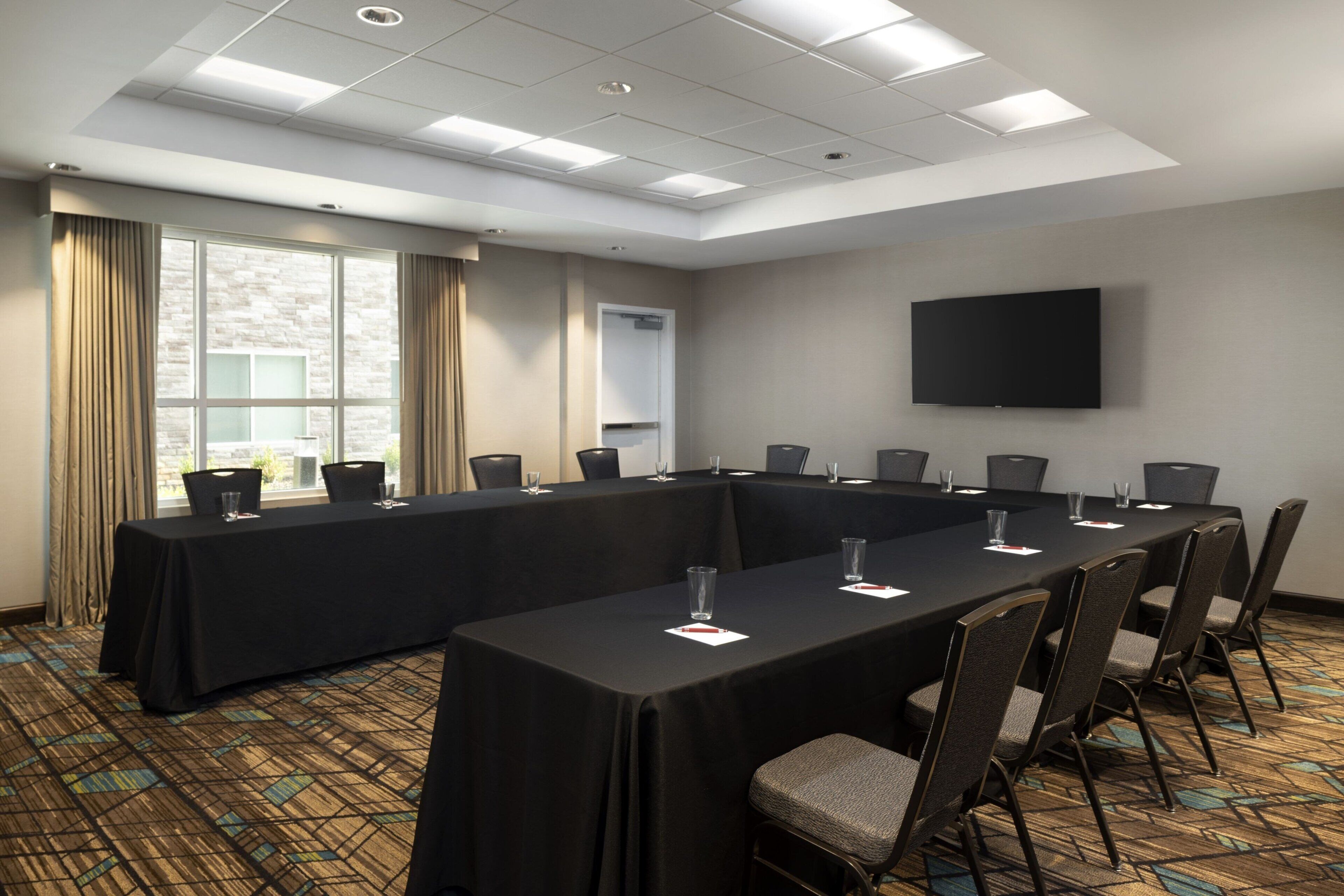 A conference room with a long table, chairs, and a flat-screen TV on the wall.