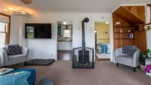 Un salon chaleureux avec une cheminée, deux fauteuils, un canapé et un téléviseur.