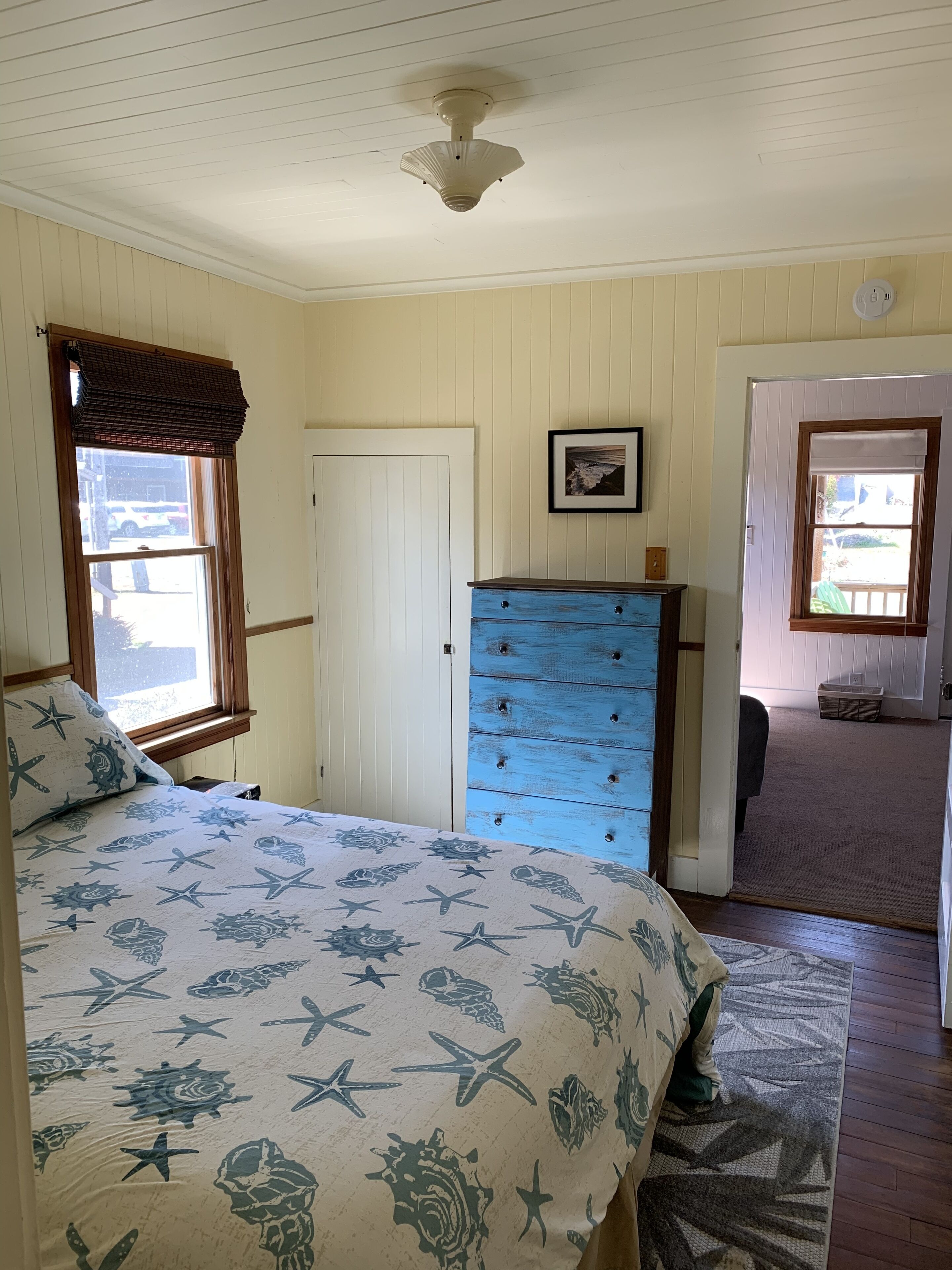 A bedroom with a bed, a dresser, a door, and a window.