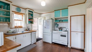 Une cuisine de taille réduite avec des meubles blancs, un réfrigérateur, une cuisinière et un évier.
