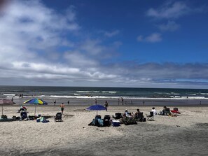 A beach with umbrellas, chairs, and people.