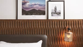 Une chambre d’hôtel avec un lit, un luminaire fixé au mur et des tableaux encadrés accrochés au mur.