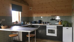 Una cocina con techo de madera, horno empotrado, fregadero y barra con taburetes.