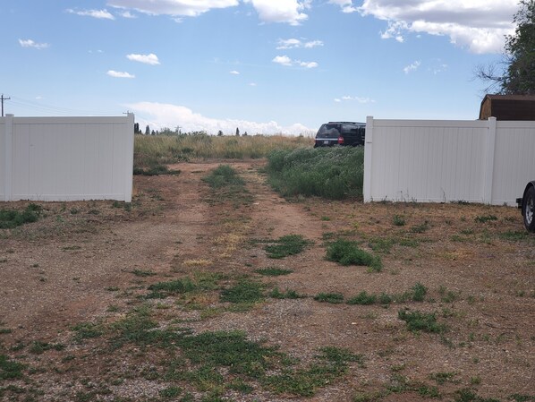 A gravel path leading to a fenced area with a vehicle parked inside. - Little House (Monticello)