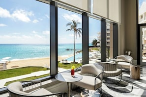 Un balcón con vista a la playa y al océano, amueblado con sillas y una mesa.