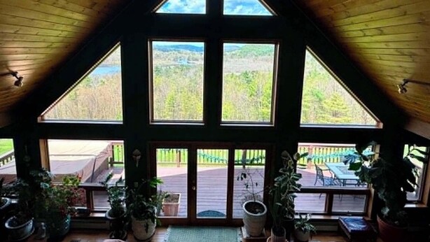 A room with a sloped ceiling, large windows, and a ceiling fan. - Chalet w/ Lake & MT views, Hot Tub, Pet friendly,  <10mins to Lake & Golf (Wells)