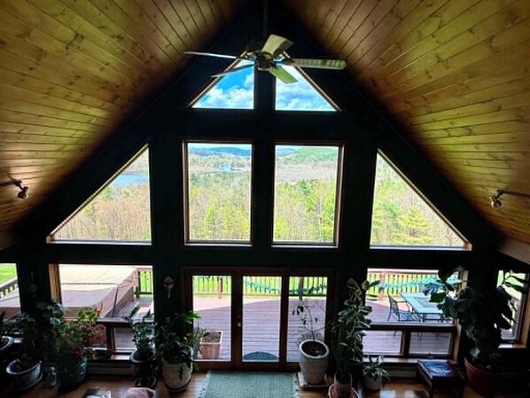 A room with a sloped ceiling, large windows, and a ceiling fan.
