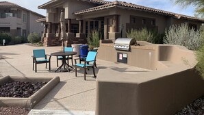An outdoor patio with a barbecue grill, seating area, and a water feature.