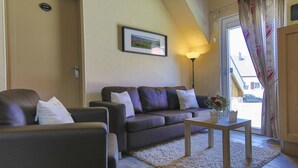 A living room with a brown leather sofa, a wooden coffee table, and a framed picture on the wall. - Gîte au pré des oies (Ostheim)