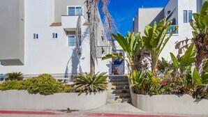 Un edificio moderno con paredes exteriores blancas, una escalera y varias plantas en macetas.