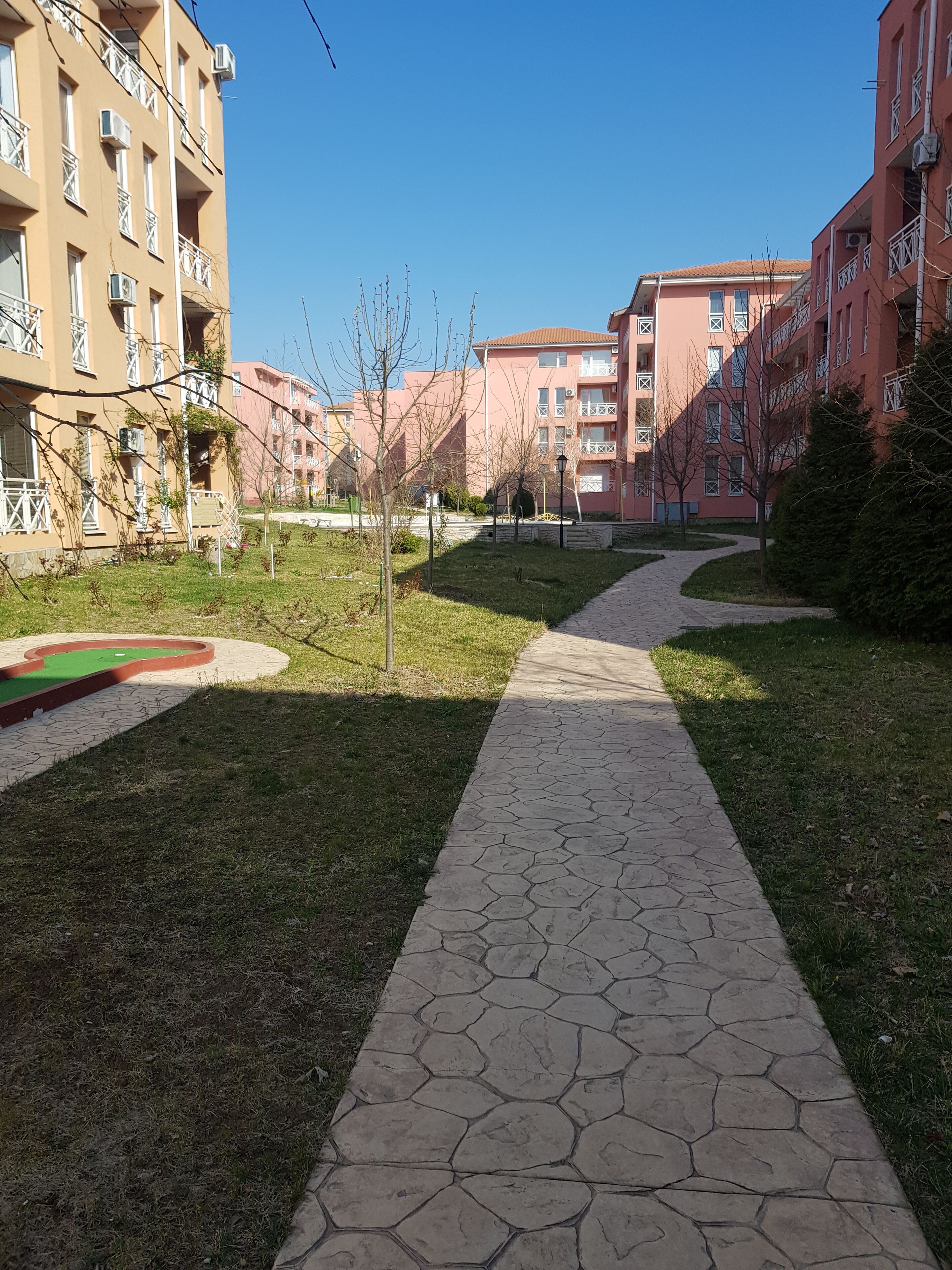 Un chemin qui traverse une cour bordée de bâtiments d’appartements de part et d’autre.