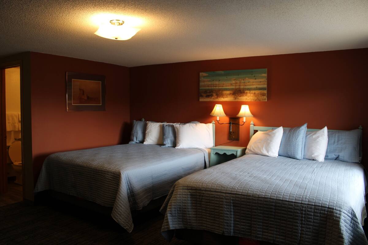 Ett hotellrum med två sängar, en tavla på väggen och två sänglampor.