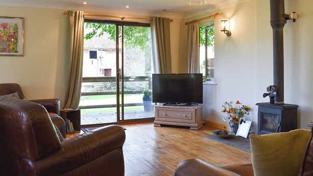 A living room with leather sofas, a flat-screen TV, a wooden cabinet, and a fireplace.