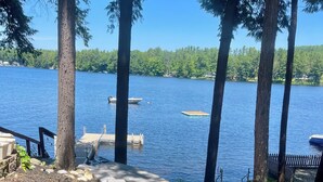 A stone pathway leading to a dock by a lake, surrounded by trees and a wooden fence. - Lake house, Dock, 3 beds/3 full baths. Pet friendly! (Shapleigh)