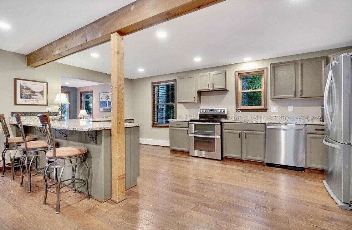 A modern kitchen with a central island, stainless steel appliances, and wooden beams.