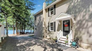 A two-story house with a front porch, a welcome sign, and a view of a lake. - Lake house, Dock, 3 beds/3 full baths. Pet friendly! (Shapleigh)