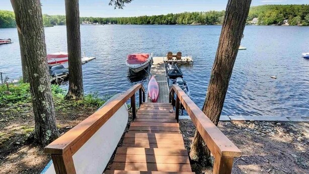 A wooden dock leading to a boat on a calm lake, surrounded by trees and boats. - Lake house, Dock, 3 beds/3 full baths. Pet friendly! (Shapleigh)