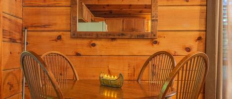 A wooden dining room with a round table, four chairs, and a mirror on the wall.