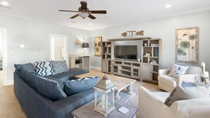 Un salon avec un canapé, une table basse, un téléviseur et un ventilateur de plafond.