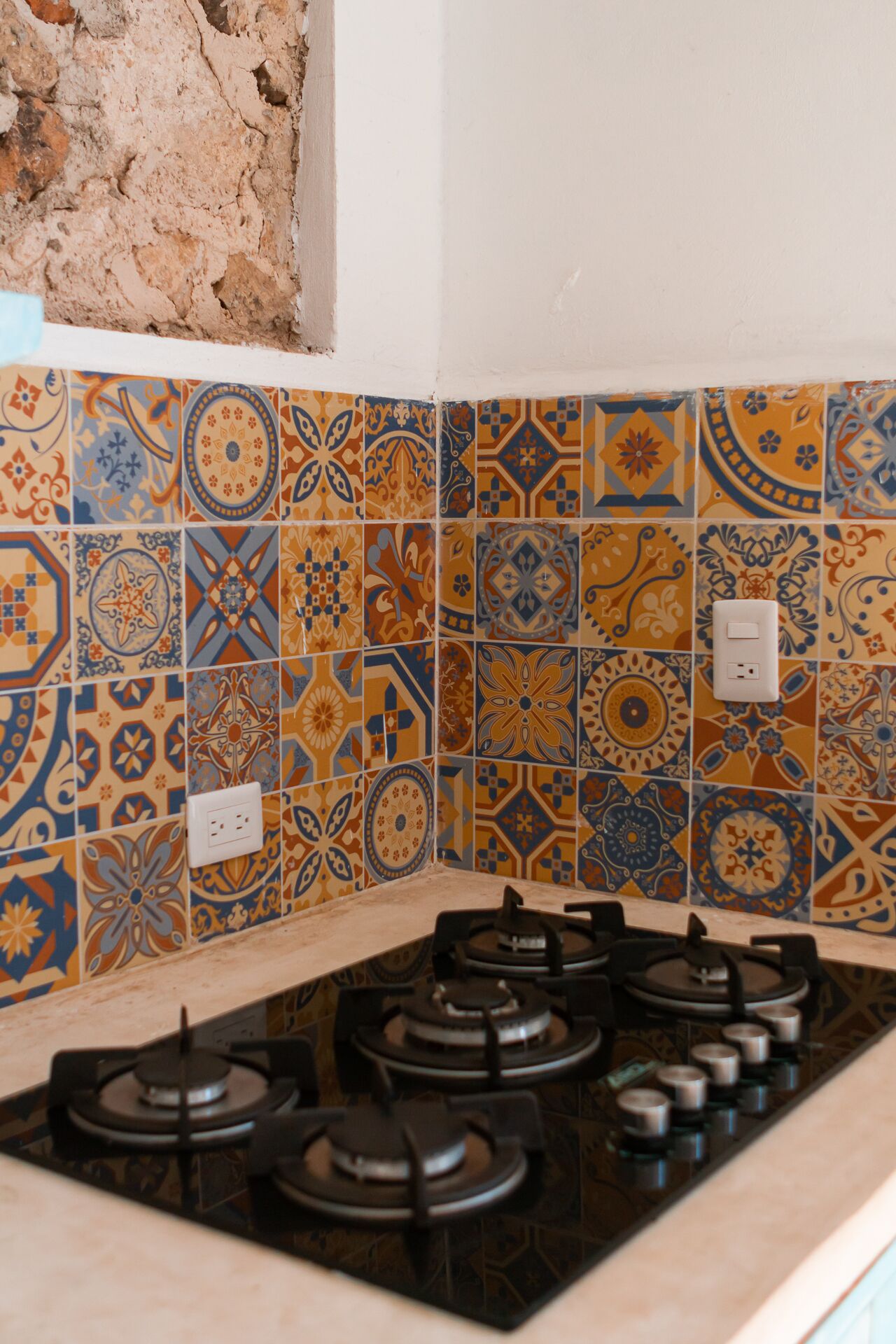 A kitchen with a gas stove and patterned tiles.