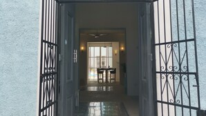 Een poort naar een gebouw met een betegelde vloer en een zichtbare eetruimte met stoelen en een tafel.