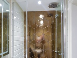 A shower with a glass door and a tiled wall.