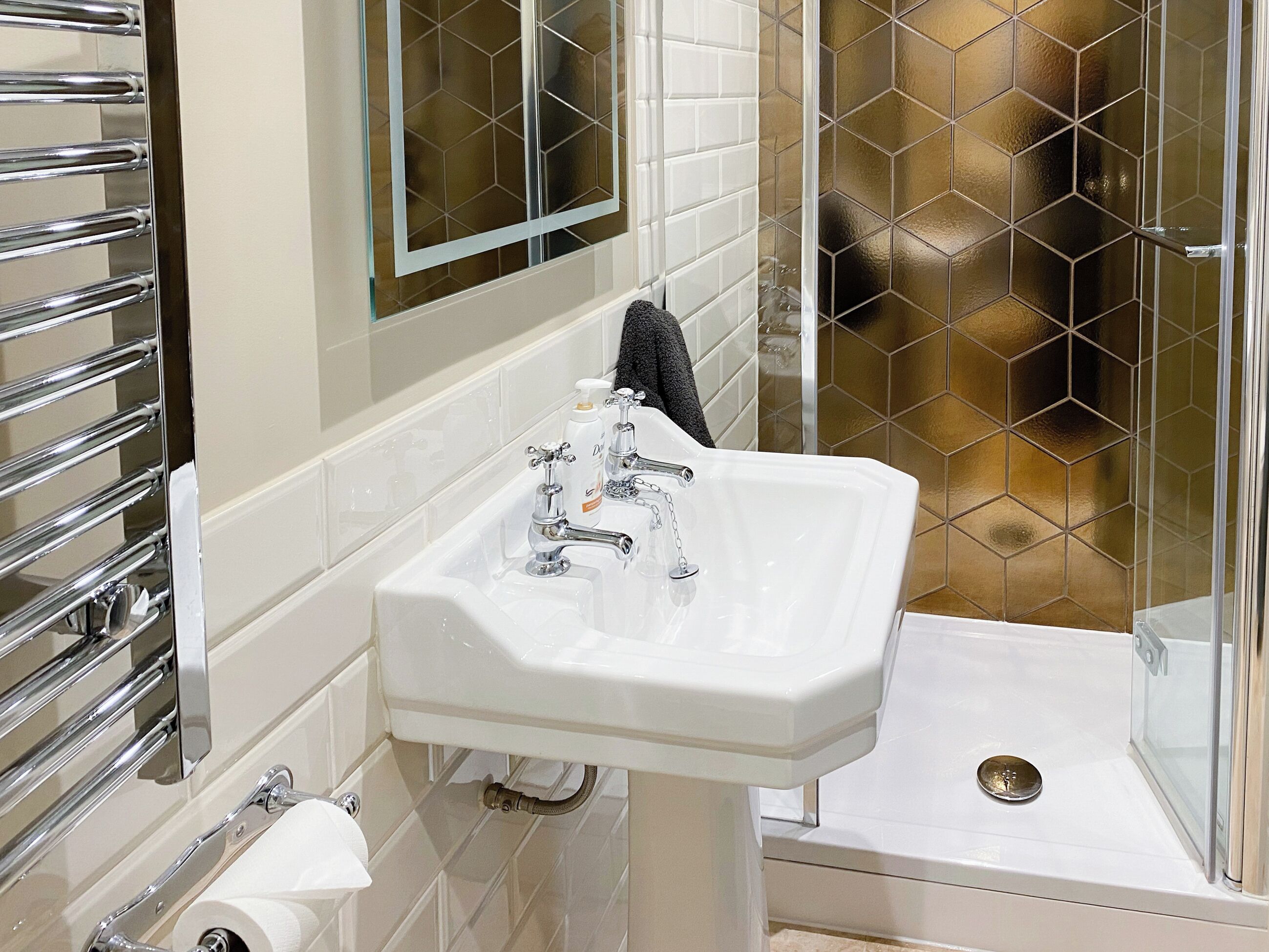 A bathroom with a white sink, chrome faucet, and a glass shower enclosure.