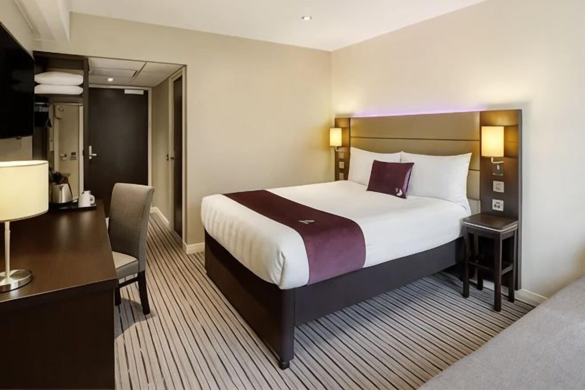 Una habitación de hotel con una cama, mesitas de noche, un escritorio y una silla.